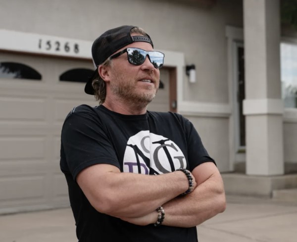 Avoid foreclosure scams by researching and asking a lot of questions. A man with arms folded stands by a garage during an interview.