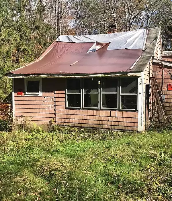 Damaged house in Lake Como due to years of poor maintenance and weather. Weather damaged home in Lake Como showing missing roof shingles, peeling paint and structural issues.